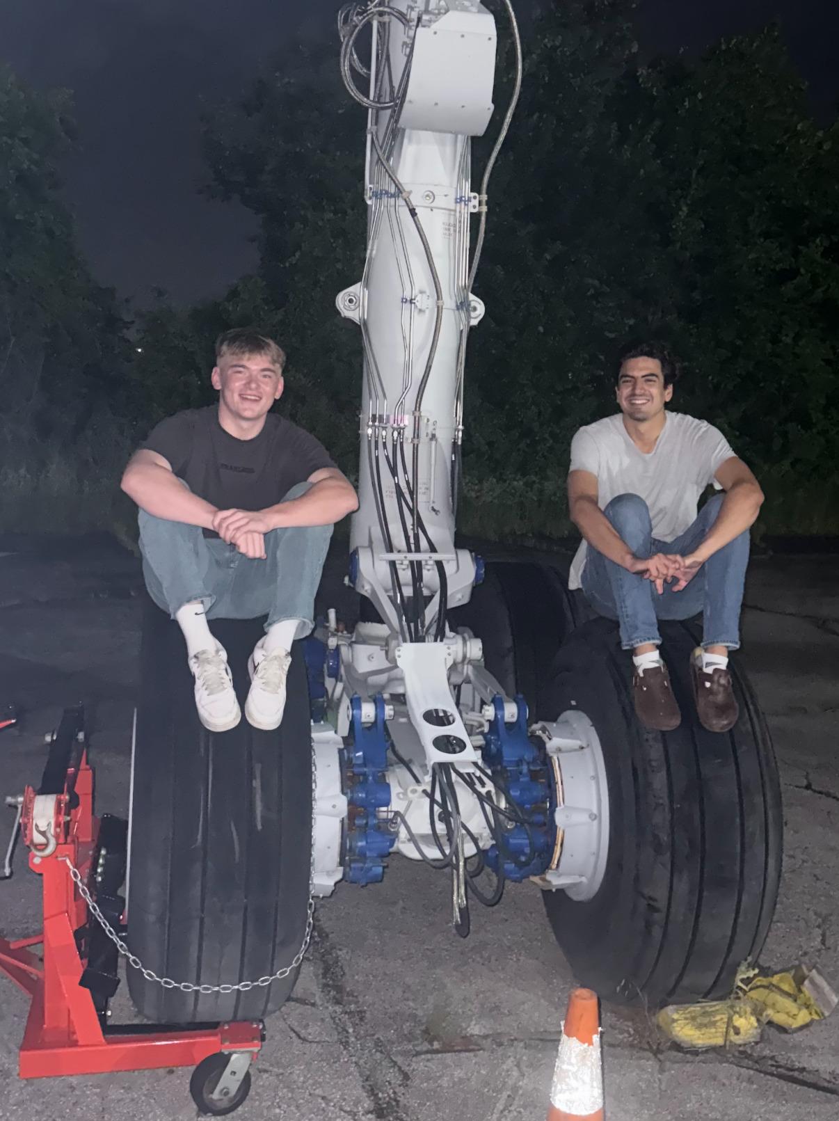 Brandon Wunderlich and a fellow Spartan College aviation student seated on a commercial aircraft landing gear assembly